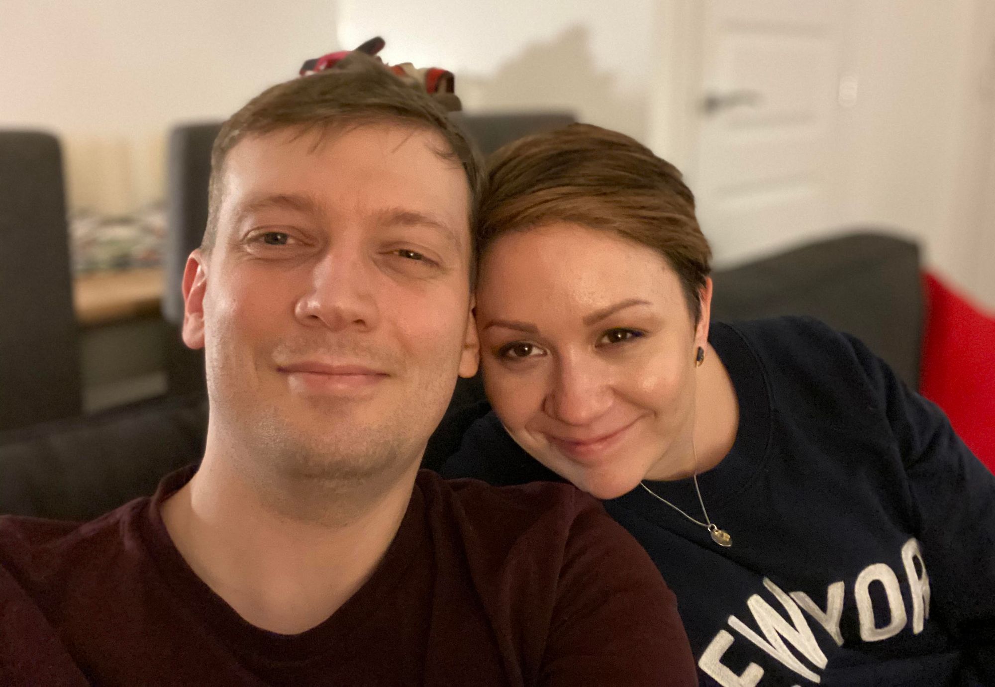 David and Jess Darnes, a man and a woman sitting closely together on a dark grey sofa