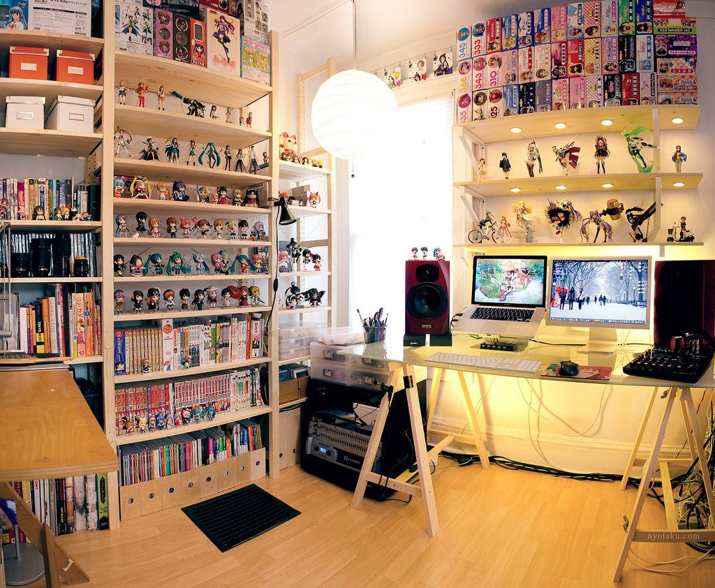 Image of a study with a MacBook Pro laptop set up and lots of Japanese manga books and anime figures