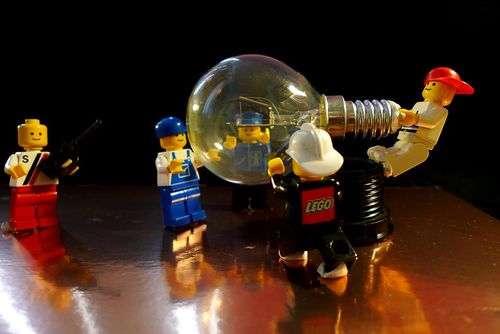 A group of LEGO minifigures trying to move a lightbulb